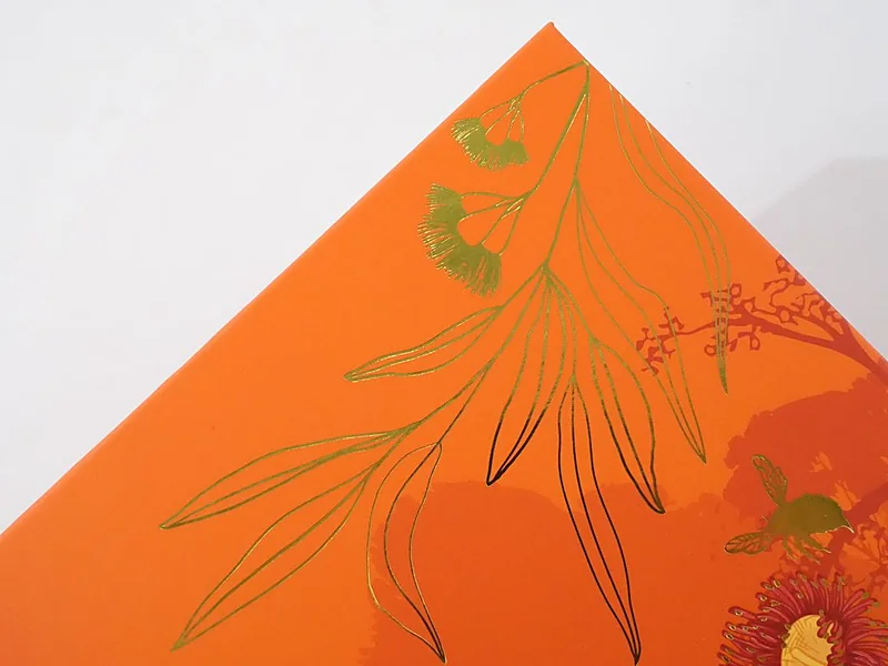 Gold foil stamped floral artwork on an orange gift box lid