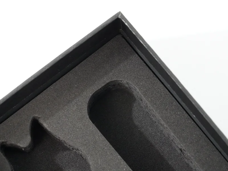 Black EVA foam tray with die-cut cavities inside a rigid box corner