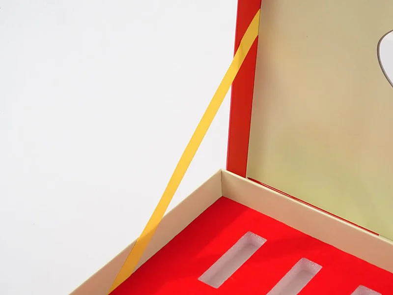 Yellow fabric pull tab lifting an insert out of a gift box