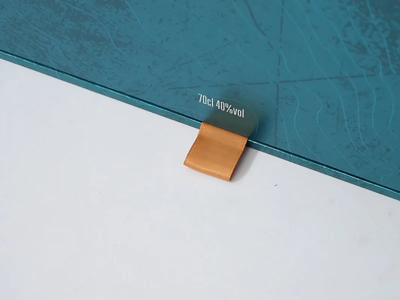 Satin ribbon pull on a textured rigid box lid